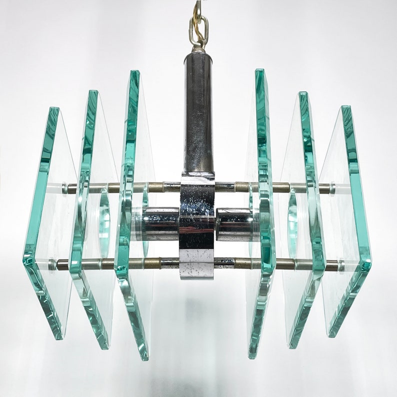 Peut inclure: Un lustre moderne en chrome et en verre avec plusieurs panneaux rectangulaires en verre. Les panneaux sont dispos&eacute;s en quinconce et sont maintenus par un cadre en chrome.