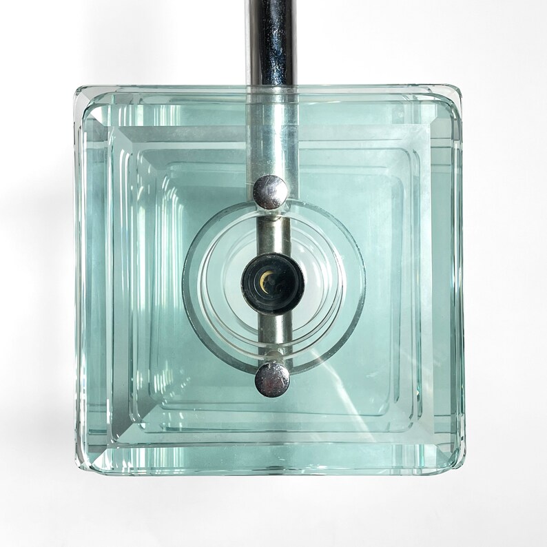Peut inclure: Un luminaire de plafond carr&eacute; en verre avec une finition chrom&eacute;e et une seule ampoule. Le verre est transparent et pr&eacute;sente un design en couches.