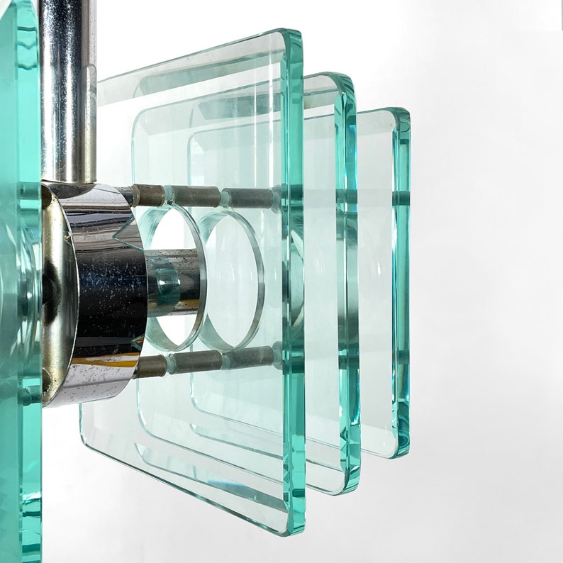 Peut inclure: Un lustre g&eacute;om&eacute;trique moderne avec plusieurs couches de carr&eacute;s de verre transparent suspendus &agrave; un cadre en m&eacute;tal chrom&eacute;.