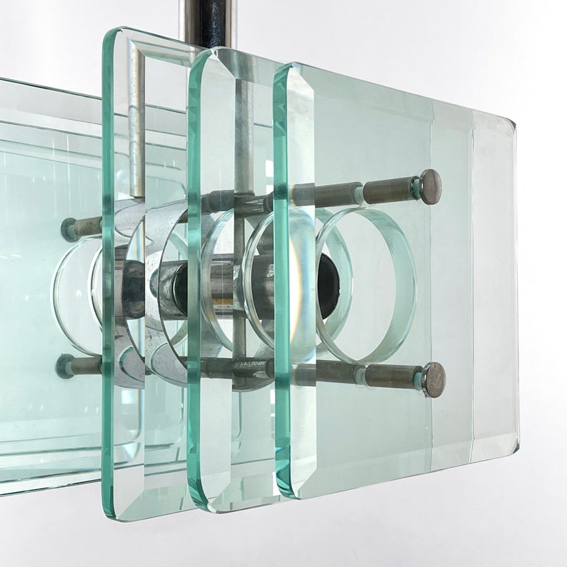 Peut inclure: Un lustre moderne et g&eacute;om&eacute;trique avec plusieurs couches de panneaux de verre transparents et une structure en m&eacute;tal chrom&eacute;. Les panneaux sont dispos&eacute;s en quinconce, cr&eacute;ant un design unique et &eacute;l&eacute;gant.