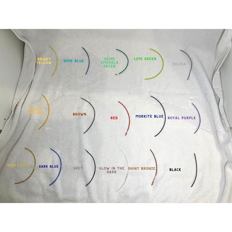 May include: A white towel with 14 different colored swatches of paint, each with a label describing the color. The colors include bright yellow, dime blue, shine emerald green, lime green, silver, brown, red, morkite blue, royal purple, shiny gold, dark blue, grey, glow in the dark, and shiny bronze.