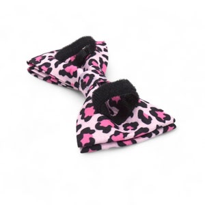 May include: Pink and black bow tie with a leopard print pattern. The bow tie has an adjustable strap.