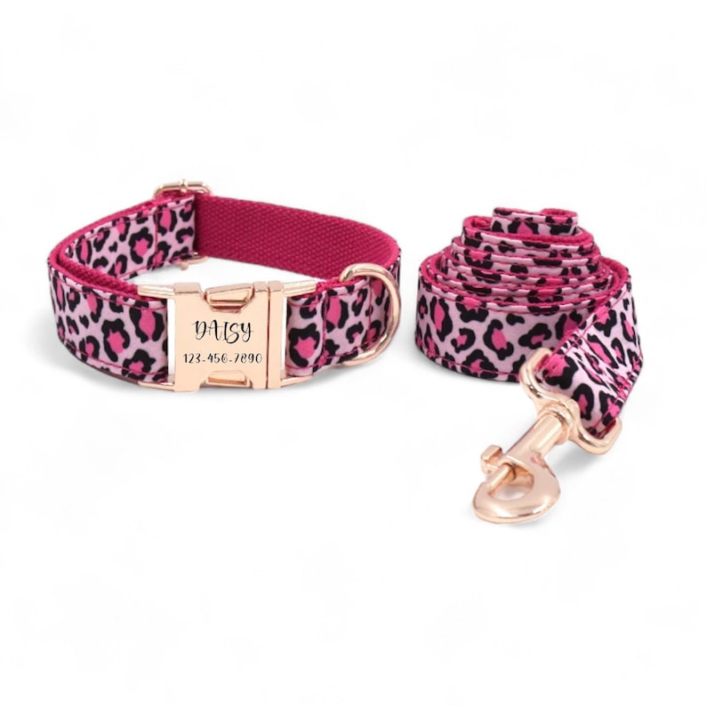 May include: Pink and black leopard print dog collar and leash set with a gold-tone buckle and a personalized name tag that reads "Daisy" and a phone number.