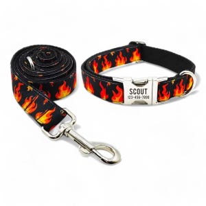 May include: Black and orange dog collar and leash set with a flame pattern. The collar has a silver buckle with the name "SCOUT" and phone number "123-456-7890" engraved on it.