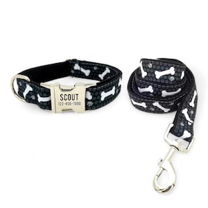 Peut inclure: Ensemble collier et laisse pour chien noir et blanc avec un motif d'os. Le collier a une boucle argentée avec le nom "SCOUT" et le numéro de téléphone "123-456-7890" gravés dessus.