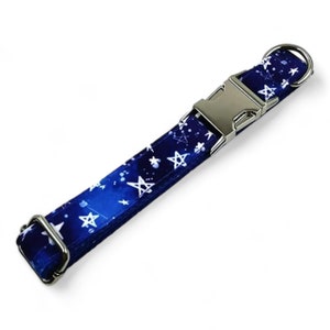 May include: A blue dog collar with a white star pattern. The collar has a silver buckle and a silver D-ring.