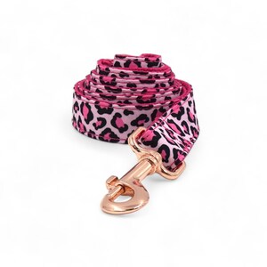 May include: Pink and black leopard print dog leash with a rose gold hook.