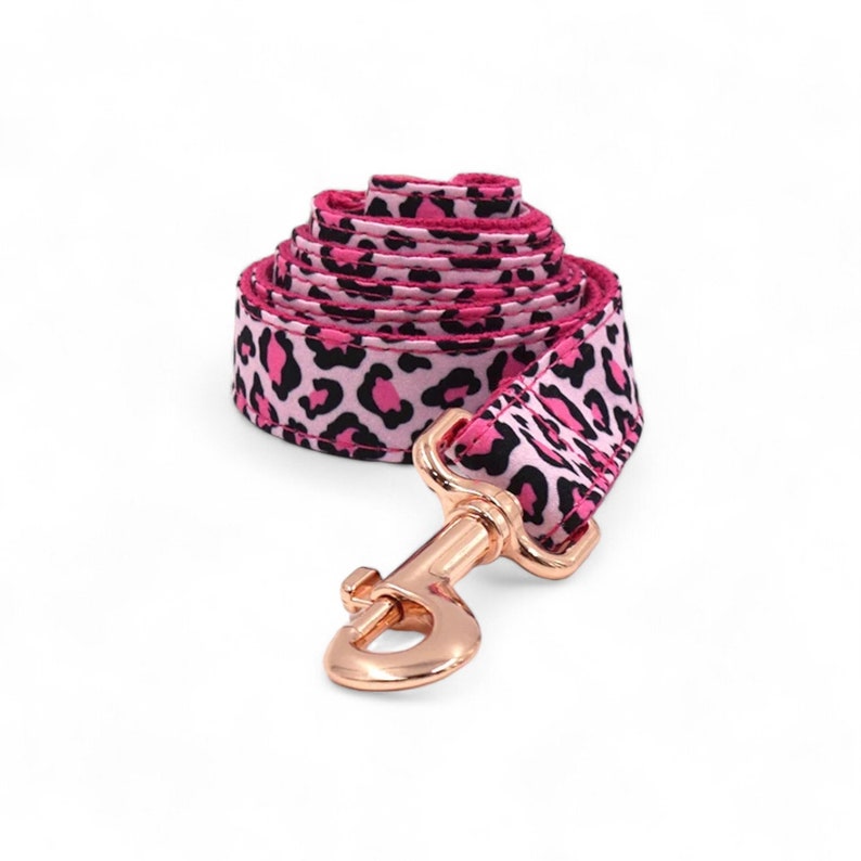 May include: Pink and black leopard print dog leash with a rose gold hook.