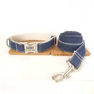 May include: A blue denim dog collar and leash set with white stitching. The collar has a silver buckle with the name "SCOUT" and phone number "123-456-7890" engraved on it.