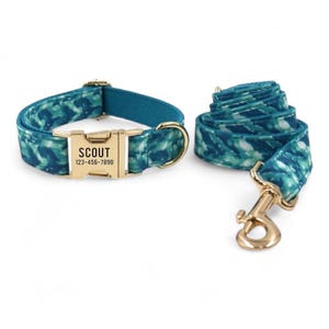 May include: A teal blue dog collar and lead set with a gold buckle and a personalised name tag that reads "SCOUT 123-456-7890".