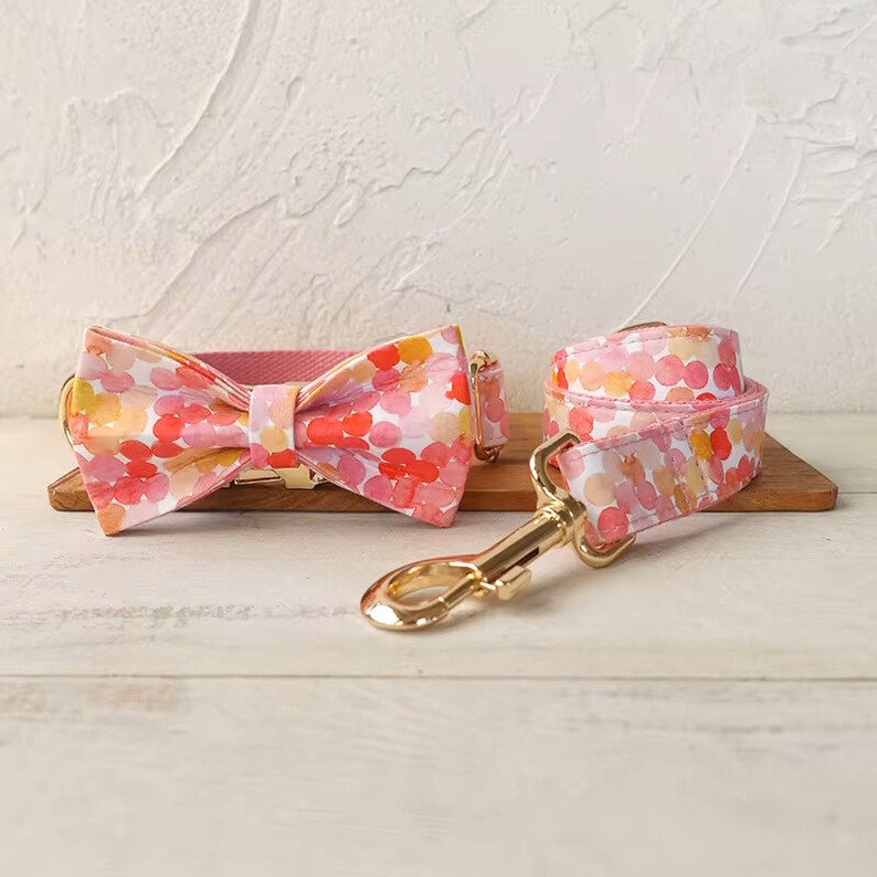 May include: A pink and orange floral dog collar and matching bow tie with a gold clasp.