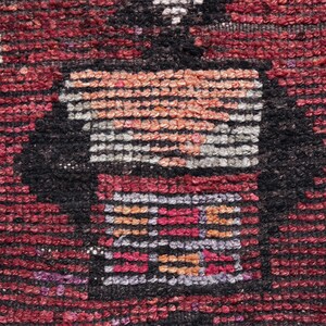 Puede incluir: Primer plano de una alfombra tejida roja, negra y blanca con un patr&oacute;n geom&eacute;trico. La alfombra tiene una superficie texturizada y est&aacute; hecha de lana.