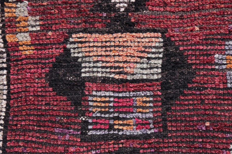Puede incluir: Primer plano de una alfombra tejida roja, negra y blanca con un patr&oacute;n geom&eacute;trico. La alfombra tiene una superficie texturizada y est&aacute; hecha de lana.