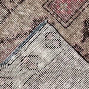 May include: Close-up of a beige and brown woven rug with a geometric pattern. The rug has a blue and white fringe border.