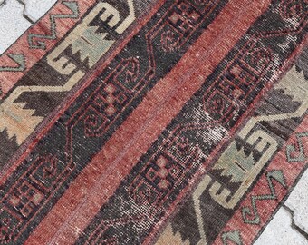 Puede incluir: Una alfombra vintage con un patrón a rayas en tonos rojos, marrones y beige. La alfombra tiene un diseño geométrico con detalles intrincados.