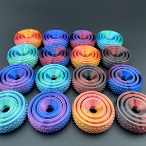 May include: A collection of 15 colorful, multi-layered, round, plastic, decorative,  knobs with a raised, textured surface. The knobs are in shades of blue, green, red, and orange.