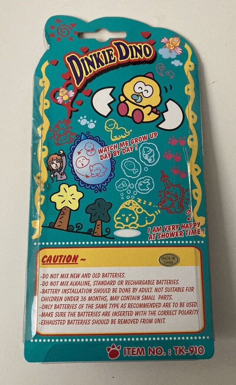 K&ouml;nnte beinhalten: Eine t&uuml;rkisblaue und gelbe Pappverpackung f&uuml;r ein Dinkie Dino Spielzeug. Die Verpackung zeigt einen Comic-Dinosaurier mit einem Schnuller und dem Text "Sieh zu, wie ich Tag f&uuml;r Tag gr&ouml;&szlig;er werde!" und "Ich bin sehr gl&uuml;cklich zur Badezeit!" Die Verpackung enth&auml;lt auch ein Warnschild mit Anweisungen zur Verwendung von Batterien.