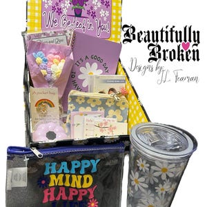 May include: A gift box with a variety of items, including a clear tumbler with daisy print, a zippered pouch with "HAPPY MIND HAPPY LIFE" text, and a notebook. The box also contains a small bouquet of colorful flowers and other stationery items.