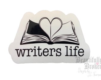 May include: A white sticker with a black and white illustration of an open book with a heart shape in the middle. The text "writers life" is below the book. The sticker has a cloud-like shape.