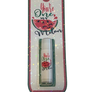 May include: A white lip balm tube with a watermelon design and the text "You're One in a Melon" on the label. The lip balm is packaged in a green and red cardboard holder with a holographic finish.