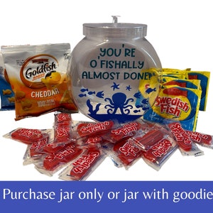 May include: A clear glass fishbowl jar with a blue octopus design and the text "You're O'Fishally Almost Done!"  The jar is filled with bags of Swedish Fish candy and a bag of Goldfish crackers.
