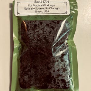 May include: A green package containing dark-colored material. The package has a white label with the text "Bank Dirt" and "For Magical Workings Ethically Sourced in Chicago Illinois, USA."