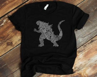 May include: Black t-shirt with a gray silhouette of Godzilla made from newspaper print.