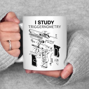 Può includere: Tazza in ceramica bianca con la scritta "I STUDY TRIGGERNOMETRY" in nero. La tazza presenta un diagramma dettagliato di una pistola smontata. La tazza è tenuta da una persona che indossa un maglione grigio.