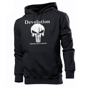 Può includere: Felpa con cappuccio nera con una grafica bianca di un teschio con un design di bandiera americana. Il testo "Devolution" e "Patriots are in control" è stampato sotto il teschio.