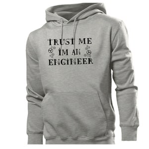 以下が含まれることがあります： グレーのフード付きスウェットシャツで、前面に「TRUST ME I'M AN ENGINEER」という文字がプリントされています。文字の周りは小さな歯車の記号で囲まれています。