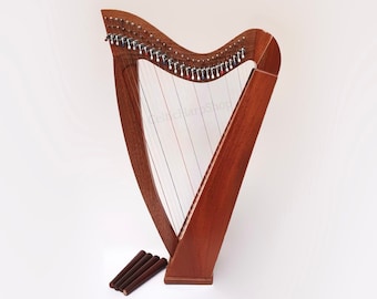 May include: A wooden Celtic harp with strings and a natural wood finish. The harp is standing on a white surface.