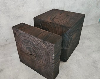May include: Two dark brown wooden blocks, one stacked on top of the other. The top block is square, while the bottom block is rectangular. Both blocks have a natural wood grain pattern.