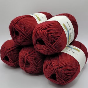 Puede incluir: Cinco ovillos de lana merino superwash de color rojo intenso, cada uno con una etiqueta blanca que dice "220 Superwash Merino 100% Superwash Merino Wool 220 yards (200 metros)"