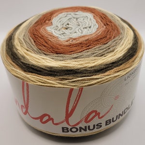 Op de afbeelding: Een grote, veelkleurige bol wol met een kleurovergang van crème, bruin en roest. Het garen is in een cirkelvormig patroon gewikkeld. Het label luidt "Mandala BONUS BUNDLE".
