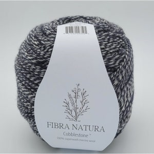 May include: A skein of black and white yarn with a label that reads "FIBRA NATURA Cobblestone 100% superwash merino wool".
