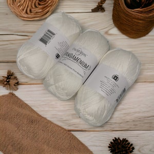 Op de afbeelding: Drie witte bollen Cascade Yarns Pandamonium garen, een mix van katoen en viscose. Het etiket vermeldt "55% Katoen / 45% Viscose (from Bamboo)".