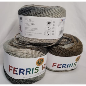 Könnte beinhalten: Drei Knäuel Ferris Wheel Garn in einer braunen, beige und grauen Farbkombination. Das Garn ist 100% Acryl und maschinenwaschbar. Das Etikett lautet "Ferris Wheel" und "Lion Brand Yarn Company".