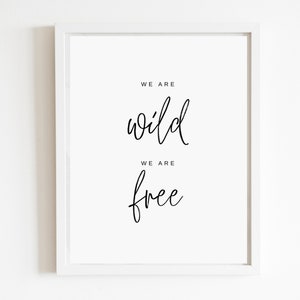 May include: White framed print with black calligraphy that reads "We are wild, We are free".