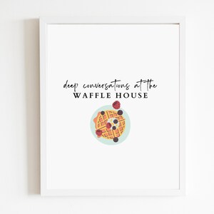 May include: A white framed print with the text "deep conversations at the WAFFLE HOUSE" and a cartoon illustration of a waffle with blueberries and raspberries on a blue plate.