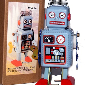 Puede incluir: Un juguete robot de hojalata vintage con llave de cuerda, pintado en azul claro, rojo y plateado. El robot tiene un resorte en la cabeza, indicadores y un panel de pecho detallado. La caja al lado tiene el texto "MS294" y "ATTENTION: THIS IS NOT A TOY FOR ADULT COLLECTORS ONLY."