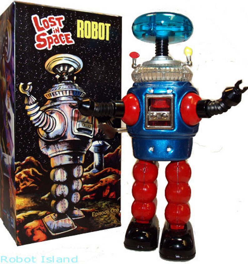 May include: A blue and red wind-up robot toy with a clear blue dome on its head. The robot is standing on a white background. The box it came in is visible in the background and says "Lost in Space Robot" on it.