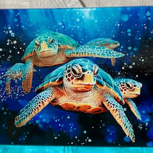 May include: A rectangular art print featuring three sea turtles swimming in a deep blue ocean. The turtles have green and brown shells, with detailed patterns. Bubbles and light effects add depth to the underwater scene.
