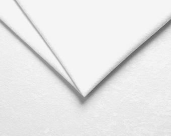 Pode incluir: Close-up de um tecido branco com uma superfície texturizada. O tecido está dobrado ao meio, criando uma dobra nítida.
