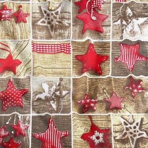 Puede incluir: Una tela con estampado rojo y blanco con un diseño repetitivo de estrellas y copos de nieve. La tela tiene un fondo rústico de madera.