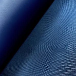 May include: A close-up shot of a textured, navy blue fabric. The fabric is folded diagonally, creating a contrast between a lighter, textured surface and a darker, shadowed area. The weave is visible.