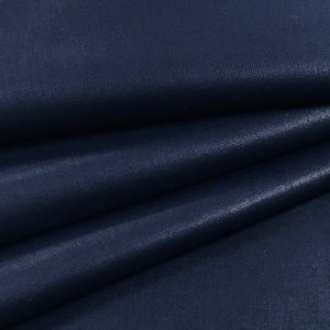 Könnte beinhalten: Nahaufnahme eines dunkelblauen Stoffes mit einem dezenten, strukturierten Muster. Der Stoff ist in mehreren Lagen gefaltet, wodurch die Tiefe der Farbe und die Textur sichtbar werden.