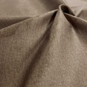 Könnte beinhalten: Nahaufnahme eines braunen Stoffes mit einer strukturierten Oberfläche. Der Stoff hat einen dezenten Glanz und ein weiches, plüschiges Gefühl.