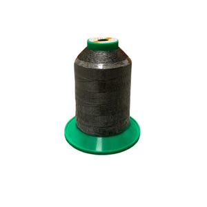 Op de afbeelding: Een spoel zwart garen op een groene plastic spoel. Het garen is strak gewikkeld en heeft een lichte glans.