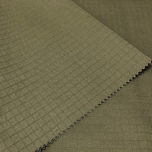 Peut inclure: Gros plan sur un tissu vert avec un motif en grille texturé. Le tissu est plié, montrant le dessous.