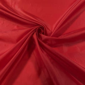 May include: A close-up of a smooth, red fabric with a soft, flowing texture.